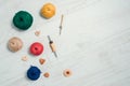 Layout of different cotton yarn balls , wooden buttons and punch needles on white wooden floor. Concept of creative handiwork