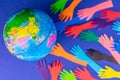 Layout of the earth and many colored hands on a blue background. The concept of saving the planet earth.