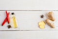 Layout of ginger and ginger oil bottle and condiments on light wooden background.