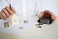 Layout of a house made of white paper and a woman& x27;s hand, a calculator on a white table. The concept of a mortgage. Royalty Free Stock Photo