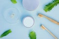 Layout of round silver cans, bamboo toothbrushes, glass cup with organic tooth paste and few green leaves. Zero waste hygiene Royalty Free Stock Photo
