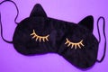 Layout. Sleep mask on a purple background. A mask in the shape of a cat& x27;s muzzle with eyelashes. The concept of a