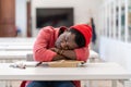 Lazy African male student falling asleep during study in library, sitting at desk sleeping on books Royalty Free Stock Photo