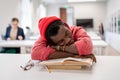 Lazy African male student falling asleep during study in library, sitting at desk sleeping on books Royalty Free Stock Photo