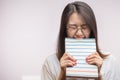 Lazy Asian student female biting a book, unwilling to study, isolated at studio.