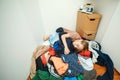 Lazy boy sleeping on the pile of thrown clothes. Mess in open wardrobe. Untidy clutter clothing closet