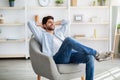 Lazy day. Relaxed arab man resting on comfortable armchair, holding hands behind head