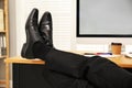 Lazy employee resting at table in office, closeup of legs