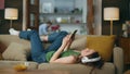Lazy girl enjoying headset music laying couch. Carefree lady browsing smartphone Royalty Free Stock Photo