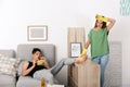 Lazy husband lying on sofa and his wife cleaning Royalty Free Stock Photo