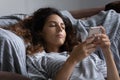 Lazy indifferent woman resting in bed, using smartphone