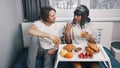 Lazy morning in bed. Young multiethnic couple drinking juice and having a breakfast in the hotel room on honeymoon Royalty Free Stock Photo