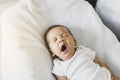 Lazy newborn baby yawning before sleep on a comfortable bed at home