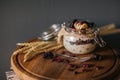 Lazy overnight oatmeal in glass jar with cherry and bananas on a dark black background on a wooden plate decorated with spikelets Royalty Free Stock Photo