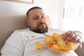 Lazy overweight man with chips sleeping on sofa, closeup
