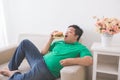 Lazy overweight man eating hamburger while laying on a couch Royalty Free Stock Photo