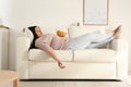 Lazy overweight woman with chips resting on sofa