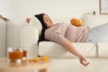 Lazy overweight woman with chips resting on sofa