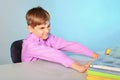 Lazy and stupid teenager does not want to learn and pushes textbooks from himself, sitting at his desk