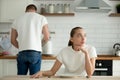 Lazy thoughtful wife sitting at kitchen table while husband cook