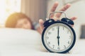 Lazy to wake up girl hand off alarm clock ring on bed Royalty Free Stock Photo