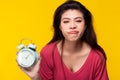 Lazy woman make expressive face and grimace face in Monday morning by holding alarm clock Sleepy girl has to wake up early morning Royalty Free Stock Photo