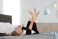 Lazy young chambermaid resting with smartphone on bed in hotel room.