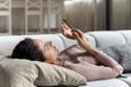 Lazy young lady rest on couch after wakeup using cellphone