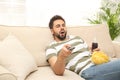 Lazy young man with chips and drink watching TV