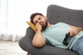 Lazy young man playing video game while lying on sofa