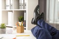 Lazy young man resting with feet on desk in office, closeup Royalty Free Stock Photo
