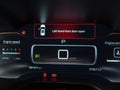 The carÃ¢â¬â¢s LCD dashboard displays a warning that the front left door is open