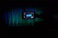 The LCD display on the camcorder. Videography in the theater. Blue-green curtain on the stage