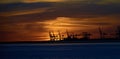 Le Havre port cranes back-lit by orange sky and clouds of a distant sunset