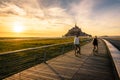 A couple of tourists biking at sunset towards the Mont Saint-Michel tidal island in Normandy, France Royalty Free Stock Photo