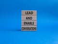 Lead and enable conversations symbol. Concept words Lead and enable conversations on wooden blocks. Beautiful blue background.