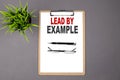 LEAD BY EXAMPLE on the brown clipboard on the grey background. Business concept Royalty Free Stock Photo