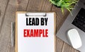LEAD BY EXAMPLE text on clipboard paper with laptop, mouse and pen Royalty Free Stock Photo