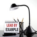 LEAD BY EXAMPLE text on notebook with pen and table lamp on the black background Royalty Free Stock Photo