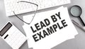 LEAD BY EXAMPLE text on paper with keyboard, calculator on grey background Royalty Free Stock Photo