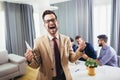 Professional business coach looking at camera posing in office with diverse happy team at background