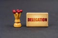 On a black surface there is a chess piece and a wooden block with the inscription - Delegation Royalty Free Stock Photo