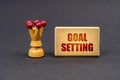 On a black surface there is a chess piece and a wooden block with the inscription - Goal setting
