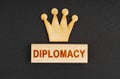 On a black surface there is a wooden crown and a block with the inscription - Diplomacy Royalty Free Stock Photo