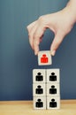 Leadership concept. Hand holding a top of wooden blocks pyramid with people icons