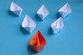 Leadership Concept - Orange color paper ship origami leading the rest of the white paper ship on blue cover background Royalty Free Stock Photo