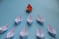 Leadership Concept - Orange color paper ship origami leading the rest of the white paper ship on blue cover background Royalty Free Stock Photo