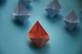 Leadership Concept - Orange color paper ship origami leading the rest of the white paper ship on blue cover background Royalty Free Stock Photo