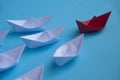 Leadership Concept - Red color paper ship origami leading the rest of the white paper ship on blue cover background Royalty Free Stock Photo