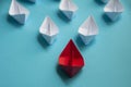 Leadership Concept - Red color paper ship origami leading the rest of the white paper ship on blue cover background Royalty Free Stock Photo